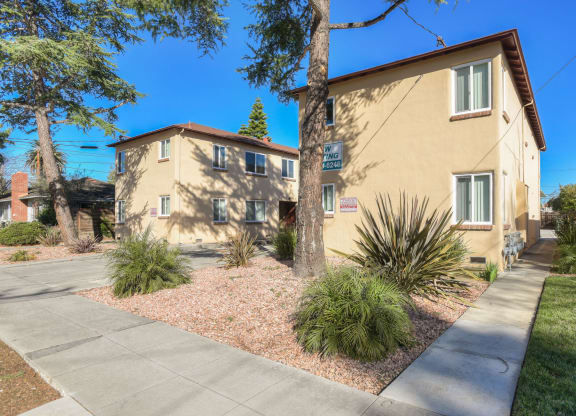 A building with a driveway and a tree in front.