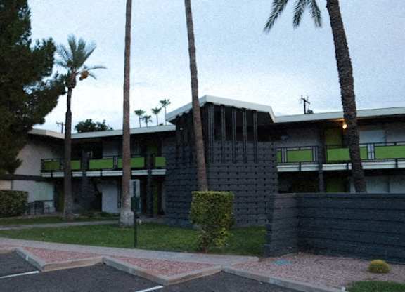 A modern house with a black fence and palm trees in front.