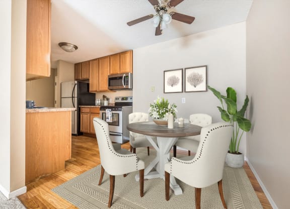 a dining area with a table and chairs and a kitchen in the background at Heritage Hills Apartments, Bloomington