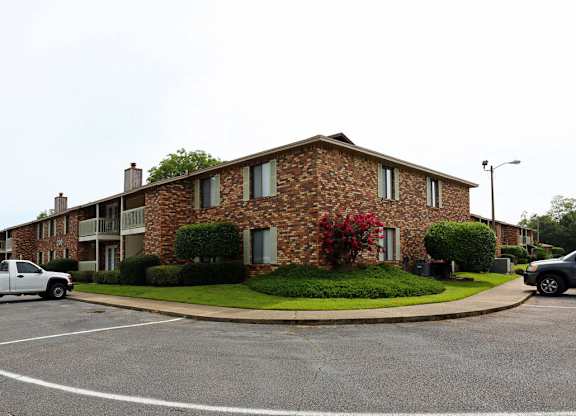 an apartment building with cars parked in a parking lot