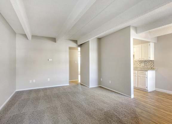 an empty living room with a kitchen in the background at Park at Fitzsimons Apartments, Colorado