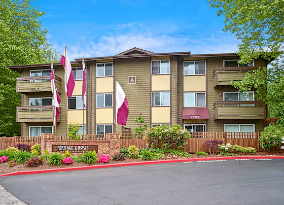 Exterior view of manicured grounds and building, and blue skies in the background at Heritage Grove, Renton, WA.