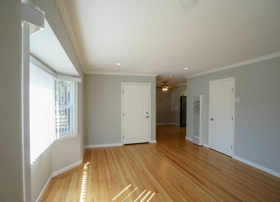 an empty living room with wood floors and a white door