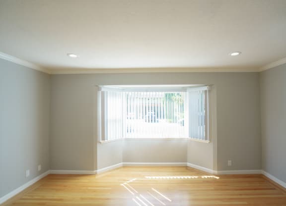 an empty room with a window and wooden floors