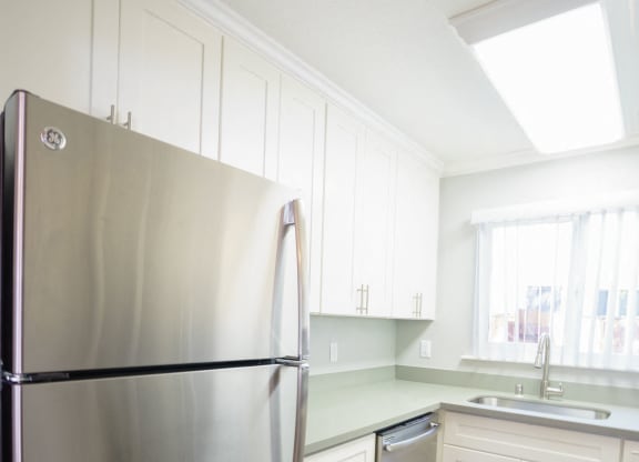 a kitchen with white cabinets and a stainless steel refrigerator