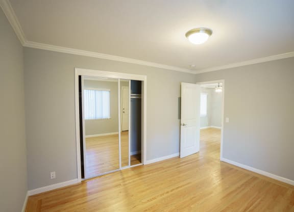 an empty living room with wood floors and a mirrored closet