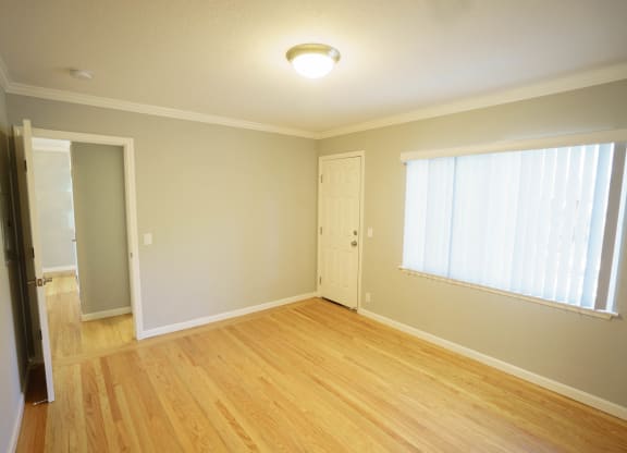 an empty living room with wood floors and a window