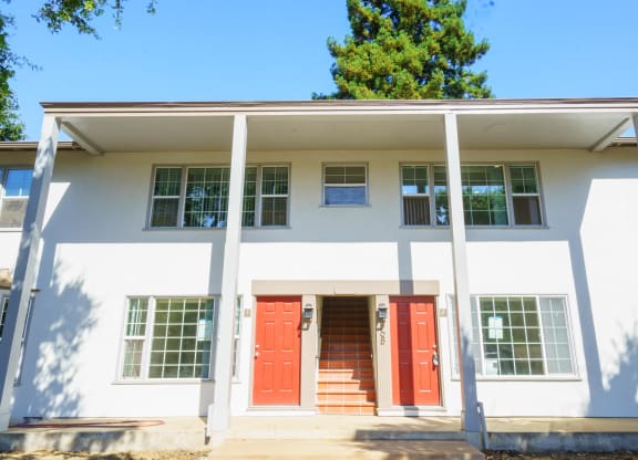 the front of a white building with red doors
