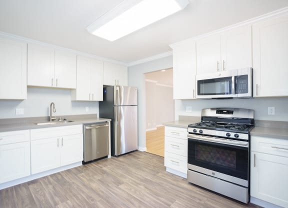 a white kitchen with stainless steel appliances and white cabinets