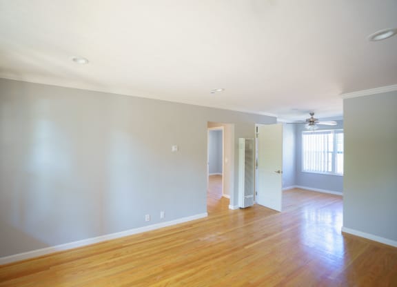 an empty living room with a hard wood floor and grey walls
