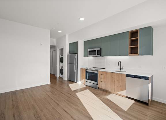 A modern kitchen with wooden floors and stainless steel appliances.