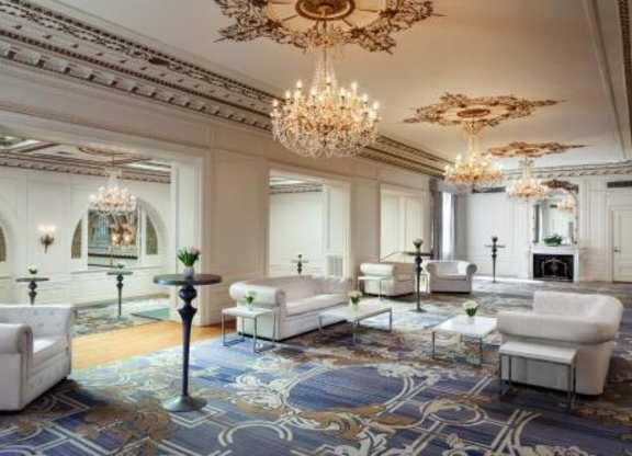 A luxurious living room with a chandelier, sofas, and a patterned rug.