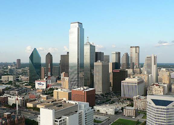 A cityscape with a variety of buildings, including a tall skyscraper with a pointed top.