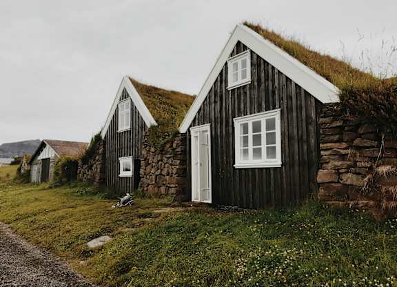 A small house with a grass roof sits in a field.
