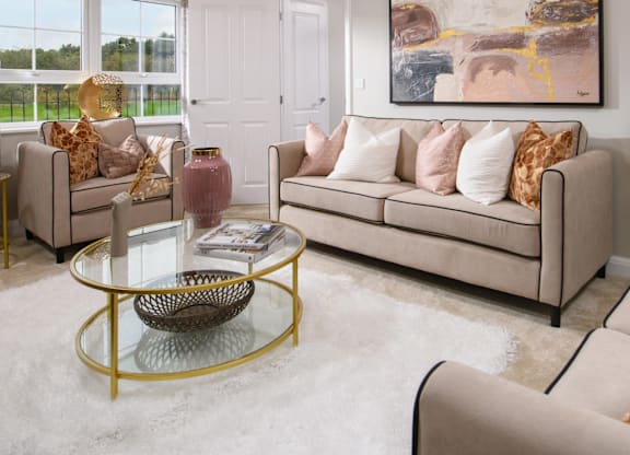 A living room with a beige couch, a glass coffee table, and a large abstract painting on the wall.