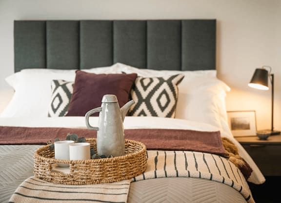 A bed with a wicker tray on top of it. at Cherrywood Apartments, D18 VY3V, DUBLIN 18