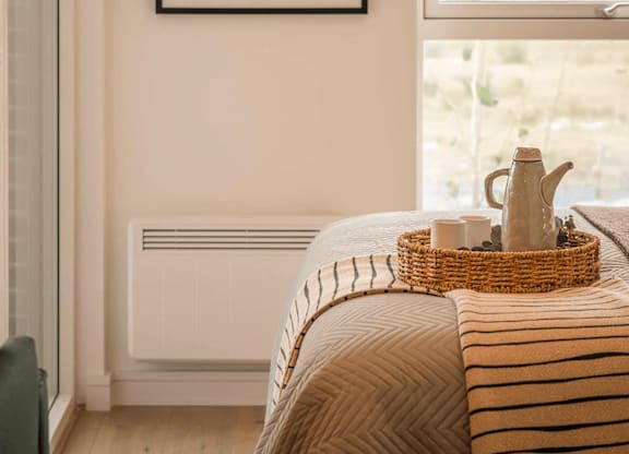 A framed artwork hangs on a wall above a bed with a basket on top of it. at Cherrywood Apartments, D18 VY3V