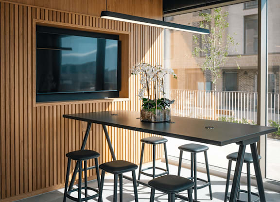 A black table with four stools in front of a wooden wall with a television. at Cherrywood Apartments, D18 VY3V, DUBLIN 18