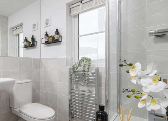 A white toilet sits in a bathroom next to a towel rack and a bottle of wine.
