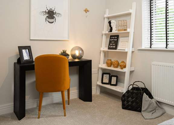 A room with a desk, chair, and shelf with items on it.