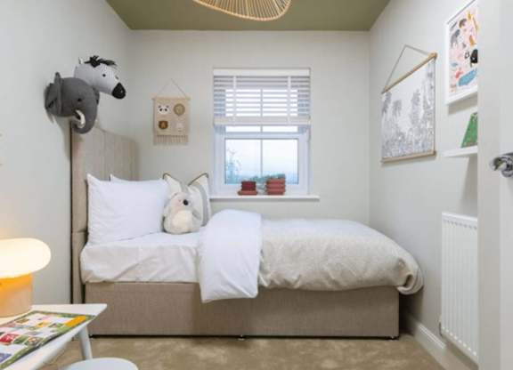 A small child's bedroom with a bed, a chair, and a window.