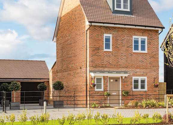 A red brick house with a pitched roof and a small window on the front.