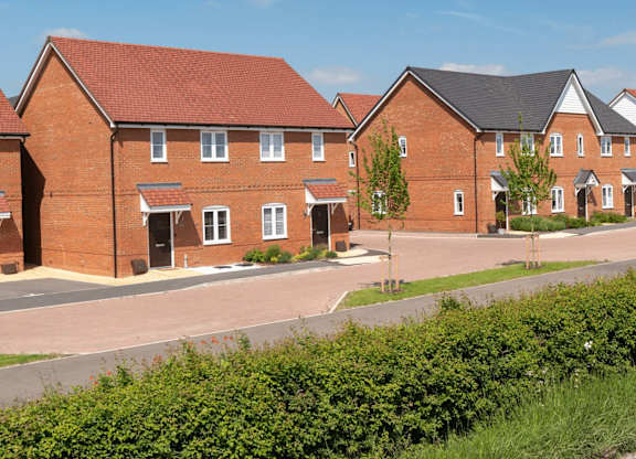 A row of red brick houses with green shrubbery in front.