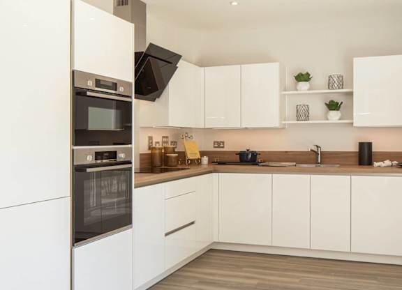 A modern kitchen with white cabinets and a wooden floor.