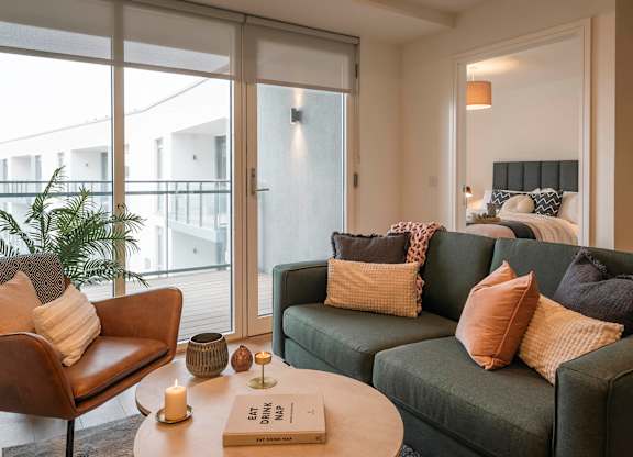 A living room with a green couch and a brown chair at Cherrywood Apartments, D18 VY3V, DUBLIN 18