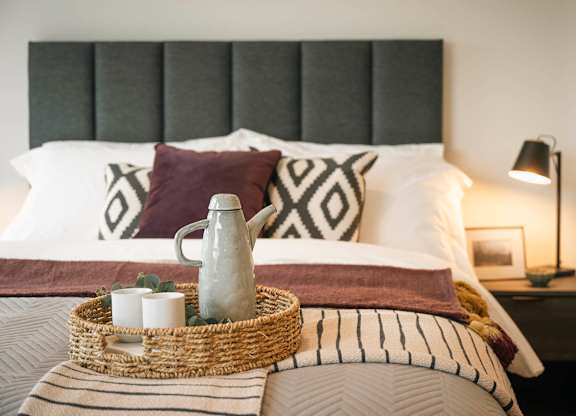A bed with a wicker tray on top of it at Cherrywood Apartments, D18 VY3V
