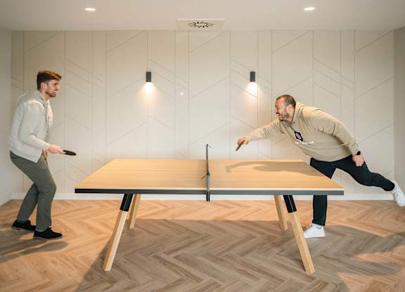 Two men playing ping pong in a room with wooden flooring at Cherrywood Apartments, D18 VY3V