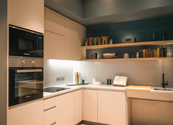 A modern kitchen with a microwave, oven, and shelves with books and other items at Cherrywood Apartments, D18 VY3V, DUBLIN 18