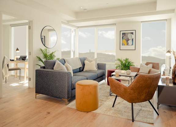 A modern living room with a grey sofa, a brown chair, and a round mirror on the wall at Cherrywood Apartments, D18 VY3V, DUBLIN 18