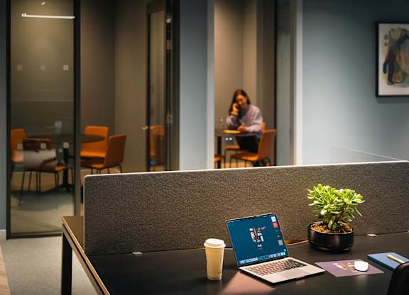 A laptop is open on a desk with a plant and a cup of coffee at Cherrywood Apartments, D18 VY3V