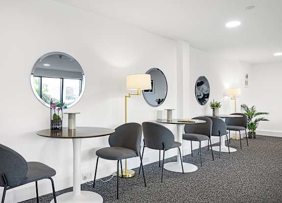 A modern dining room with grey chairs and a round table.
