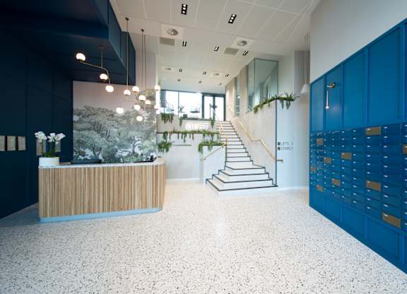 A reception area with a wooden desk and a staircase with a green plant on it.