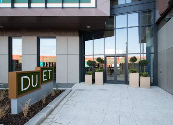 The entrance to a building with a sign that reads "DUET" in front of it.