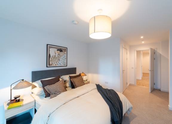 A bedroom with a large bed and a picture on the wall.