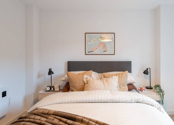 A bed with a brown blanket and tan pillows is in the image.
