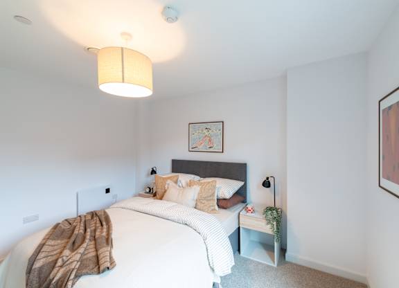 A bedroom with a bed, a nightstand, and a lamp.