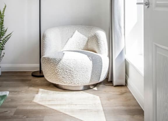 A white chair with a fluffy texture is placed in a room with a white door and a white wall at The Foundry Apartments, Bordon