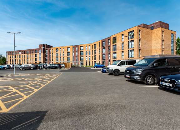 A parking lot with cars and a building in the background.
