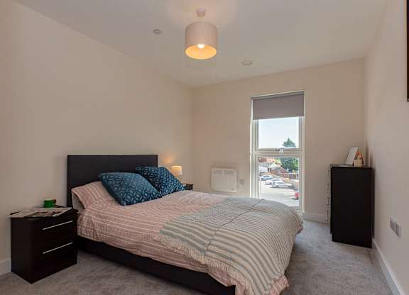 A bedroom with a bed, nightstand, and window.