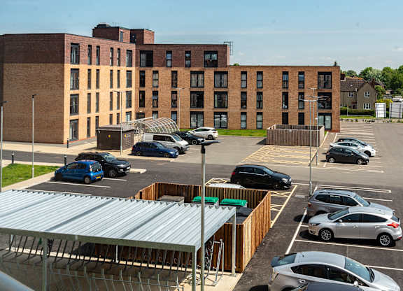 A parking lot with cars and a building in the background.