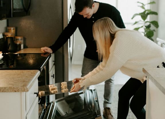 A man and a woman are cooking in a modern kitchen at The Foundry Apartments, Bordon, GU35 9FE