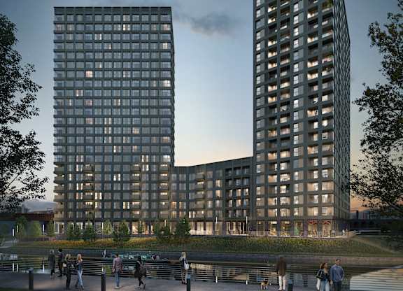 A modern building with a glass facade is surrounded by a park with people walking and sitting on benches.
