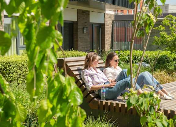 Two women sitting on bench at The Lark, London, SW11 7EA