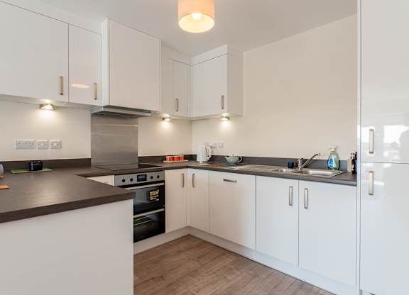 A modern kitchen with white cabinets and a dark countertop.