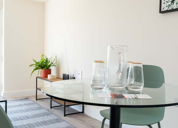 A glass table with a green chair and a potted plant.