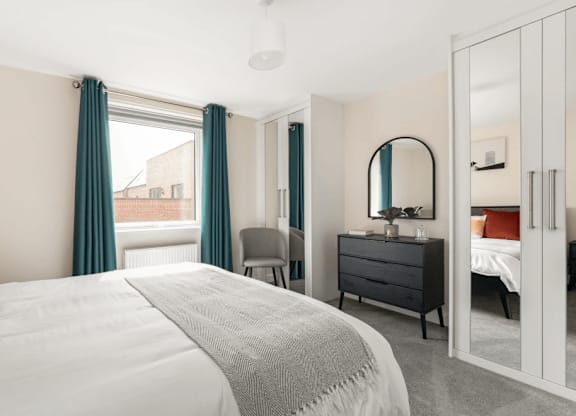 A bedroom with a large bed, a dresser, and a mirror at Origins Apartments, Cambridge, CB3 0UX